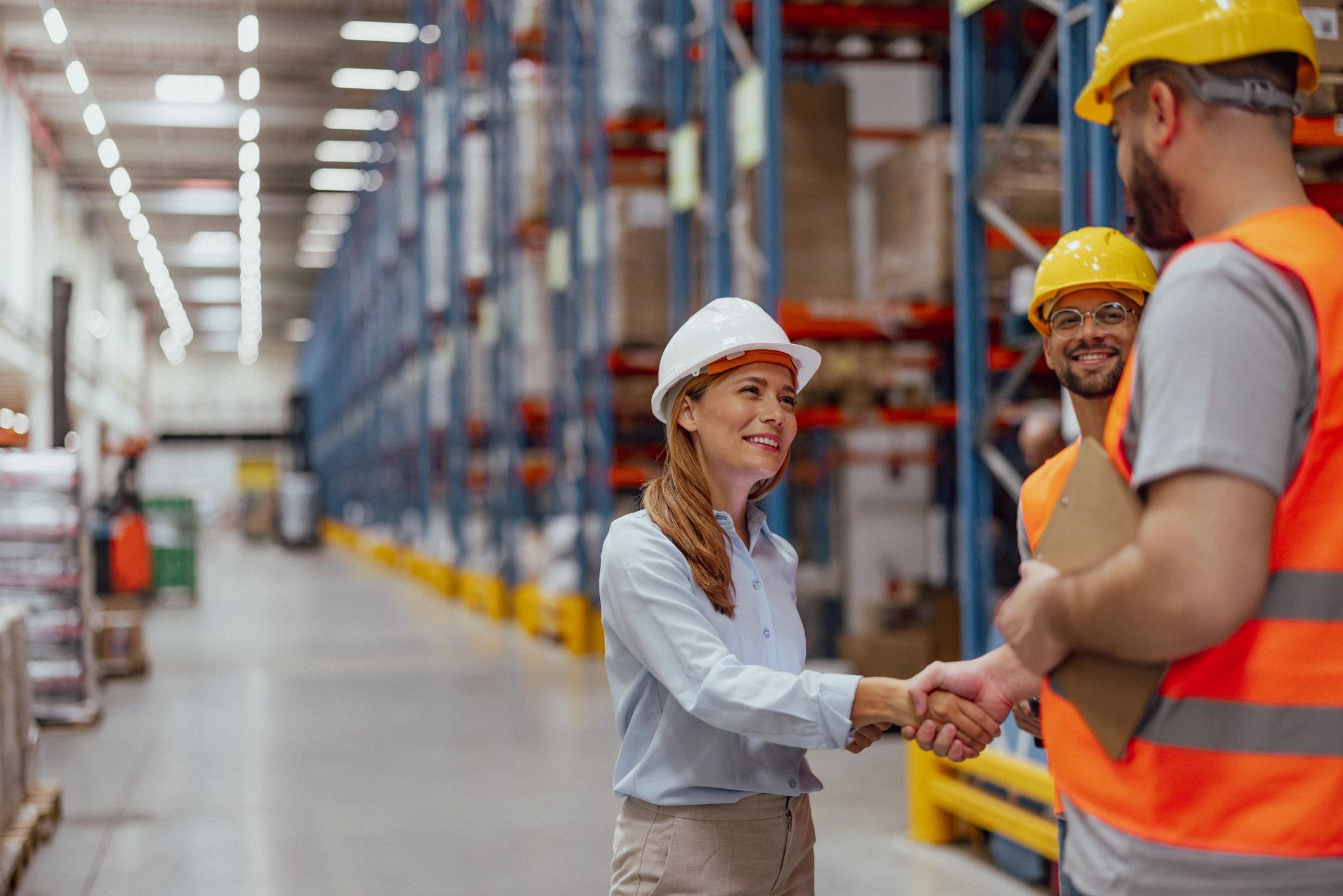 Manager and worker shaking hands in a warehouse